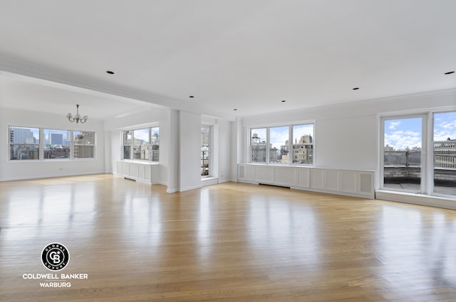 unfurnished living room with a healthy amount of sunlight, light wood-type flooring, and an inviting chandelier