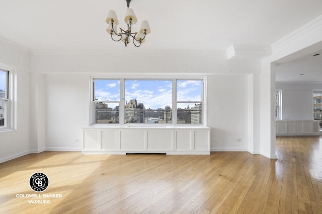 unfurnished dining area with a chandelier, light wood-type flooring, baseboards, and ornamental molding