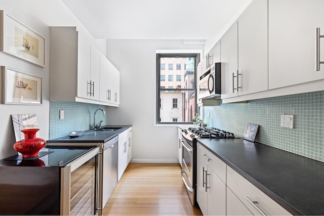 kitchen with dark countertops, baseboards, light wood-style flooring, stainless steel appliances, and a sink