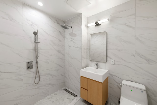 bathroom with vanity, tiled shower, toilet, and tile walls