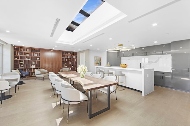 dining room with light wood finished floors, built in features, recessed lighting, and a skylight