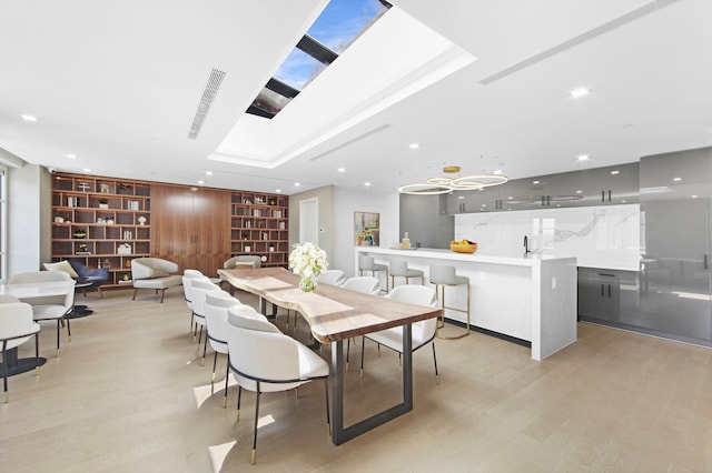 dining area with built in features, light wood finished floors, and recessed lighting