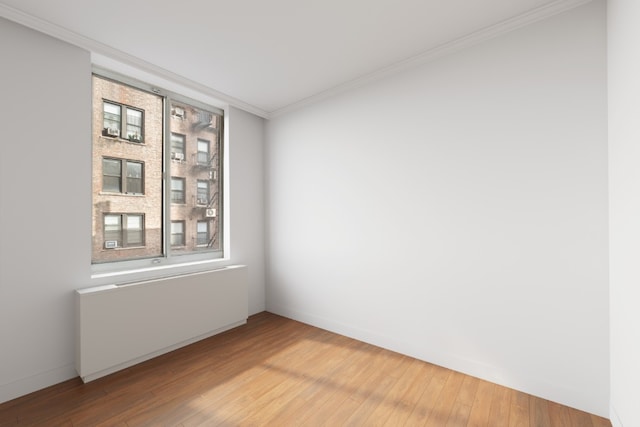 spare room featuring a healthy amount of sunlight, crown molding, and wood-type flooring