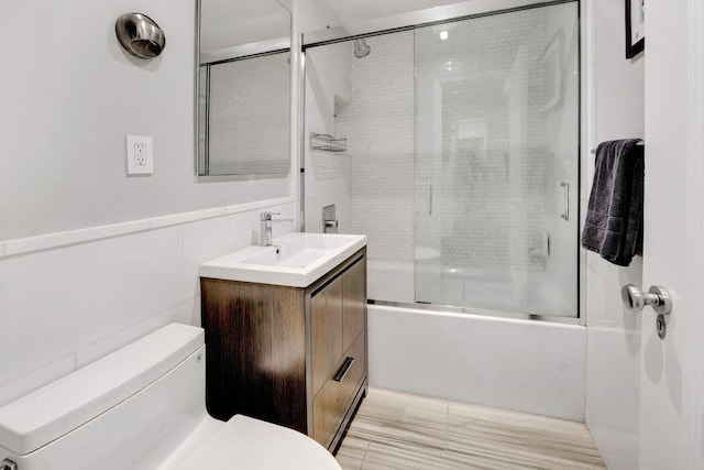 bathroom featuring vanity, enclosed tub / shower combo, and toilet