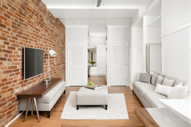 living area featuring ceiling fan, light wood-type flooring, and brick wall