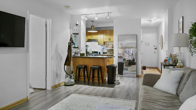 kitchen featuring dark countertops, a peninsula, light wood-type flooring, and baseboards