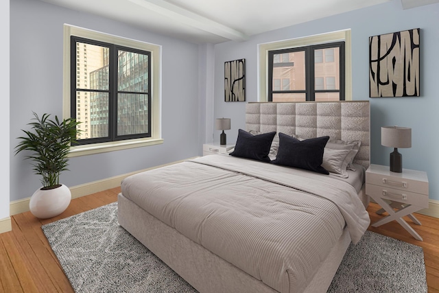 bedroom featuring beam ceiling, baseboards, and wood finished floors