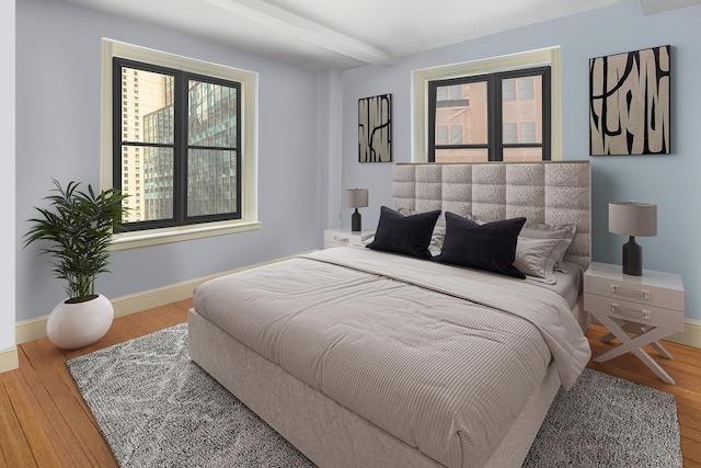 bedroom with baseboards, wood finished floors, and beamed ceiling