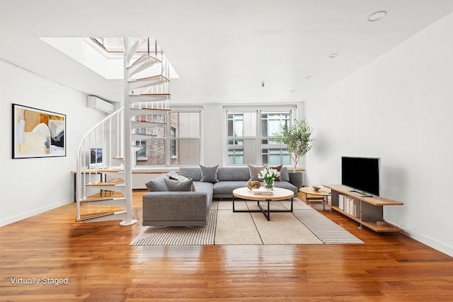 living area featuring baseboards, wood finished floors, stairs, and a wall mounted AC