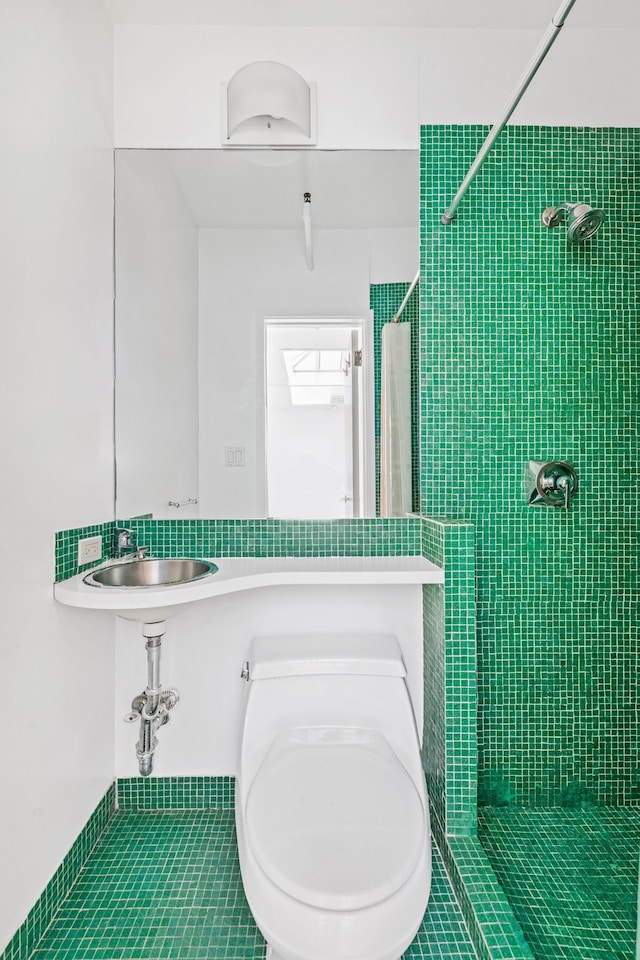 full bath featuring a sink, toilet, and tiled shower