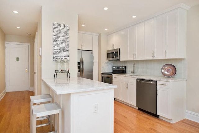 775 Riverside Dr Unit 3D, New York City, NY 10032 - kitchen featuring a sink, light wood-style flooring, a kitchen bar, and stainless steel appliances