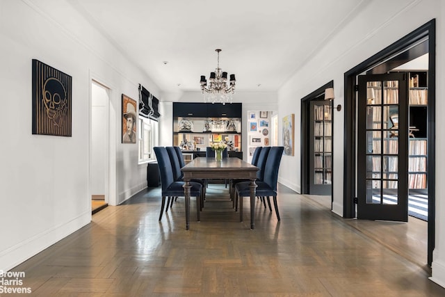 dining room featuring a notable chandelier and baseboards