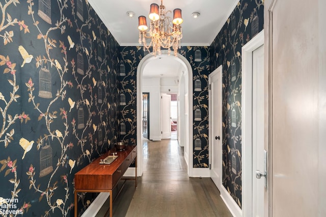 hall with wallpapered walls, crown molding, baseboards, wood finished floors, and arched walkways