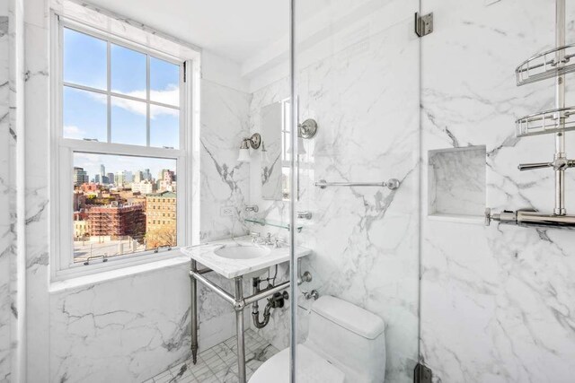 full bathroom with a city view, tile walls, toilet, and a sink