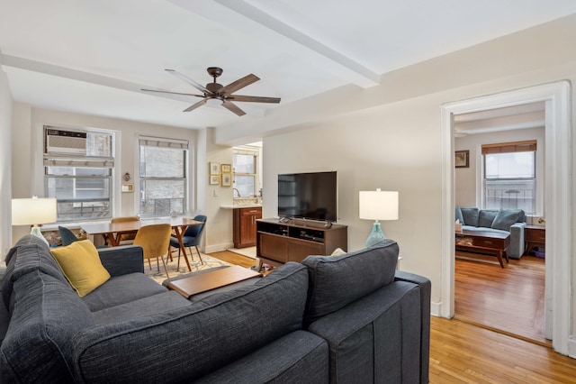 living room with beam ceiling, baseboards, light wood-type flooring, and a ceiling fan