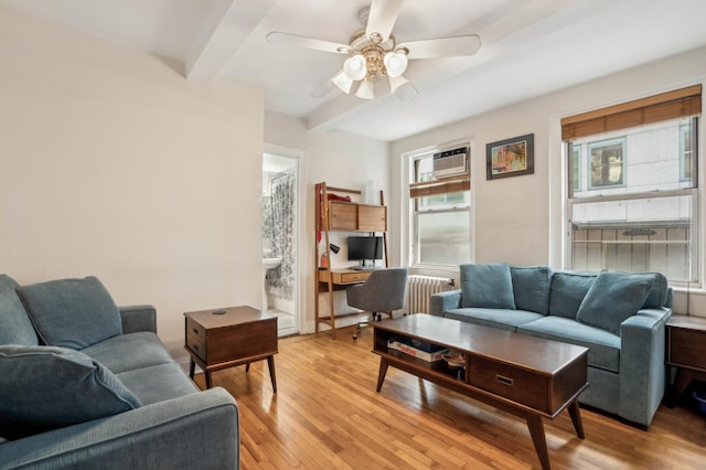 living room featuring beamed ceiling, light wood-style flooring, and a ceiling fan