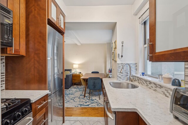 333 E 43rd St Unit 110/111, New York City, NY 10017 - kitchen featuring a sink, black microwave, stainless steel fridge, decorative backsplash, and light stone countertops