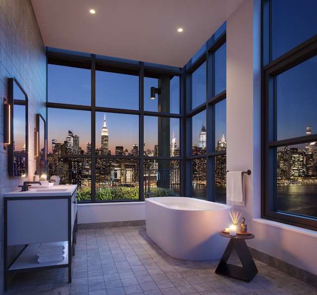 full bath with a view of city, recessed lighting, baseboards, a soaking tub, and vanity