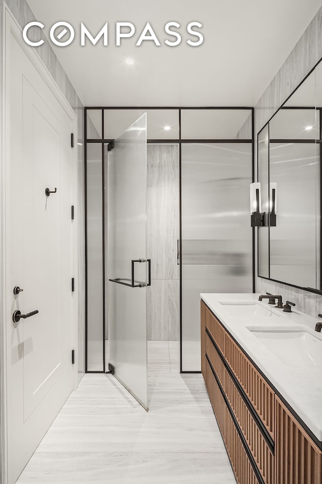 bathroom featuring double vanity, a shower stall, and a sink