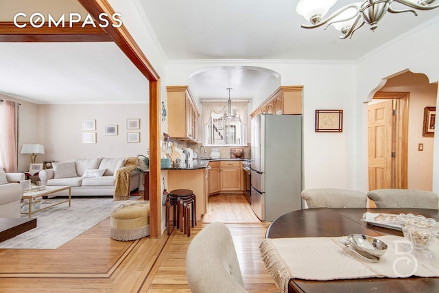 dining space featuring light wood-type flooring, arched walkways, a chandelier, and crown molding