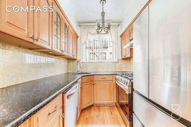 46-10 28th Ave, New York City, NY 11103 - kitchen featuring an inviting chandelier, glass insert cabinets, light wood-style flooring, appliances with stainless steel finishes, and a sink