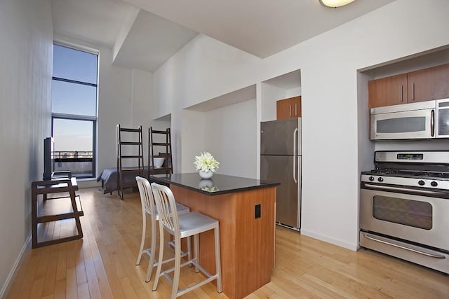 kitchen with stainless steel appliances, light wood-style floors, a breakfast bar area, and a center island