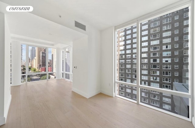 unfurnished room featuring visible vents, wood finished floors, and expansive windows