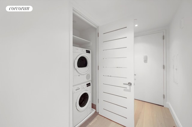 laundry room with light wood-type flooring, stacked washer and clothes dryer, and laundry area