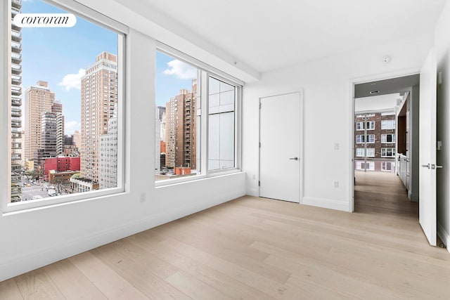 501 3rd Ave Unit 12E, New York City, NY 10016 - empty room featuring wood finished floors, a city view, and a smoke detector