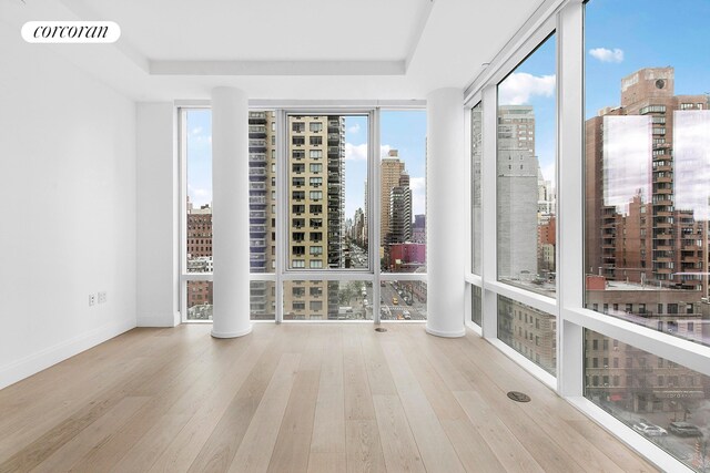501 3rd Ave Unit 12E, New York City, NY 10016 - spare room with expansive windows, a view of city, plenty of natural light, wood finished floors, and a tray ceiling
