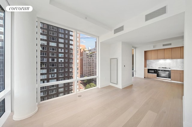 spare room with light wood finished floors, visible vents, and a view of city