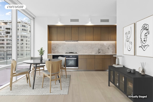 kitchen with visible vents, wall oven, backsplash, light wood-type flooring, and modern cabinets