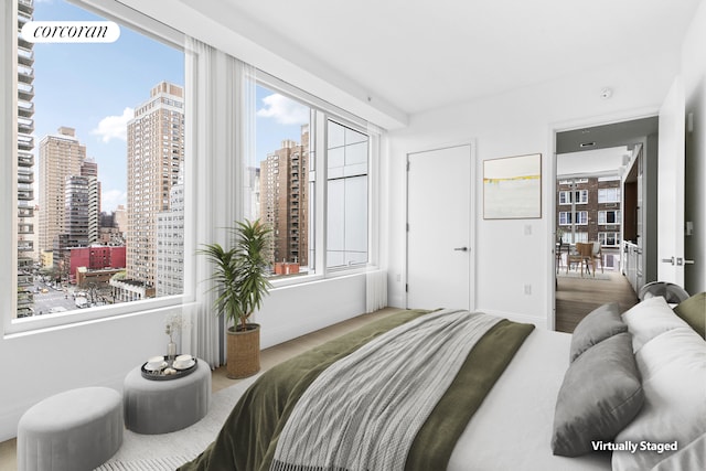 bedroom featuring baseboards, wood finished floors, and a view of city