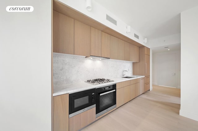 kitchen with visible vents, a sink, decorative backsplash, black appliances, and light countertops