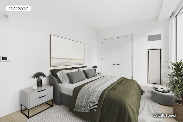 bedroom featuring light wood-style flooring, visible vents, and a closet