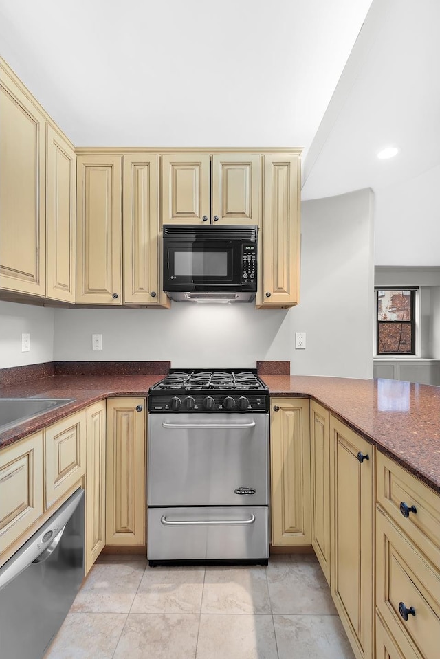 kitchen with black microwave, gas range oven, light tile patterned floors, cream cabinets, and stainless steel dishwasher