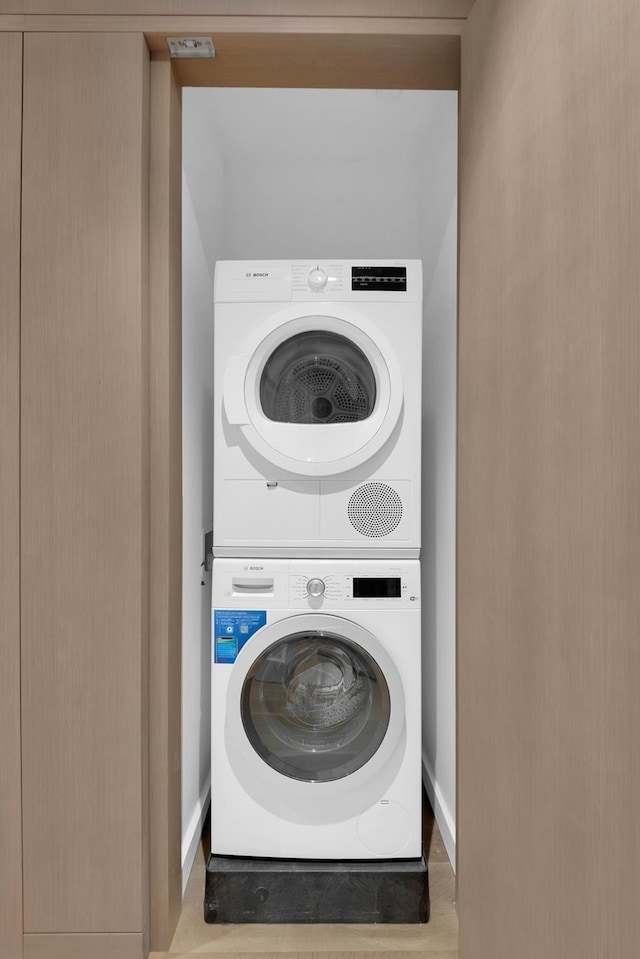 laundry room featuring wood finished floors, laundry area, and stacked washing maching and dryer