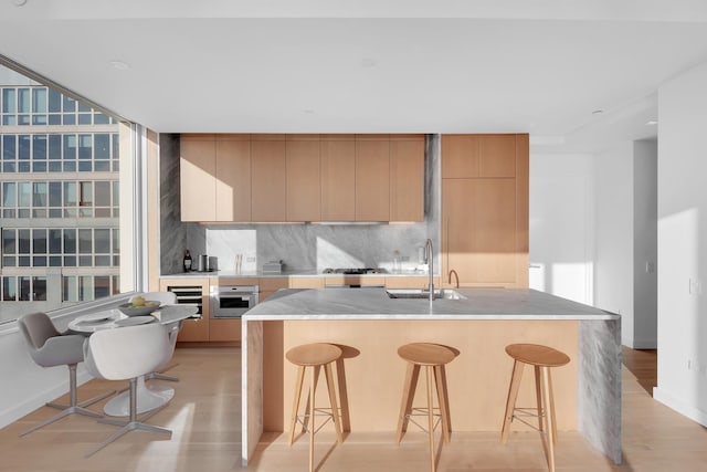 kitchen featuring backsplash, modern cabinets, a kitchen bar, and a sink