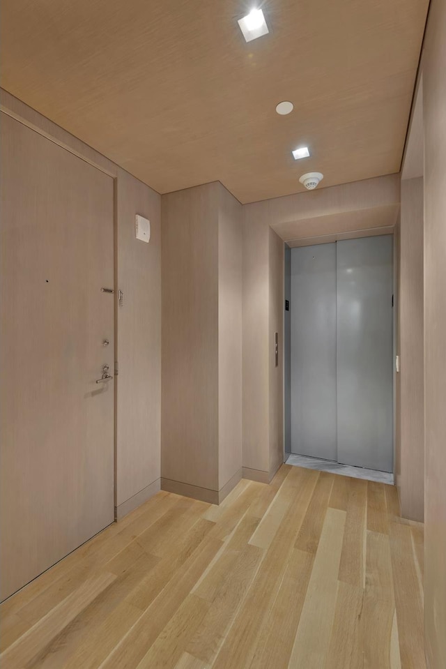 hall with light wood-type flooring and elevator