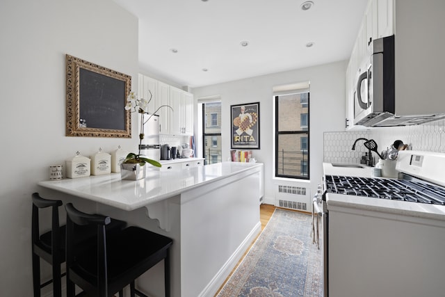 kitchen with light countertops, a kitchen breakfast bar, stainless steel appliances, a peninsula, and white cabinetry