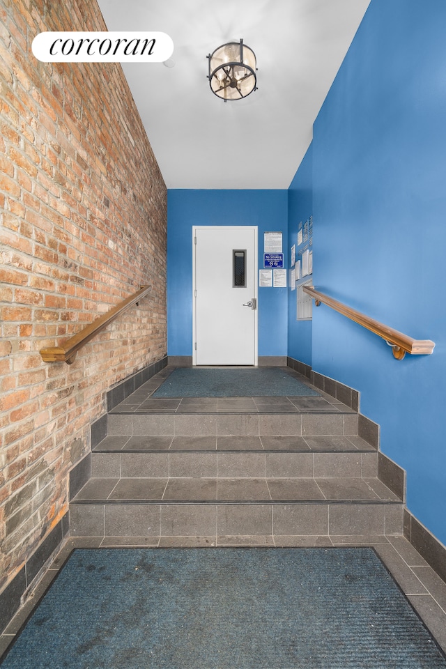 staircase with baseboards and brick wall