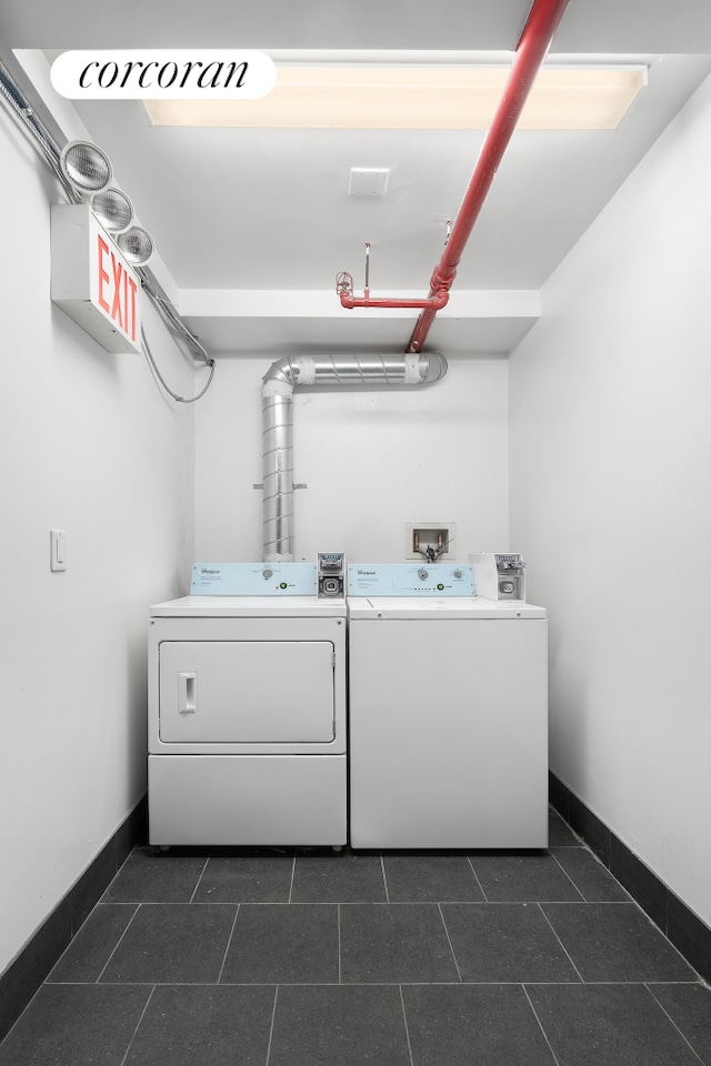 washroom with dark tile patterned floors, baseboards, washing machine and dryer, and laundry area