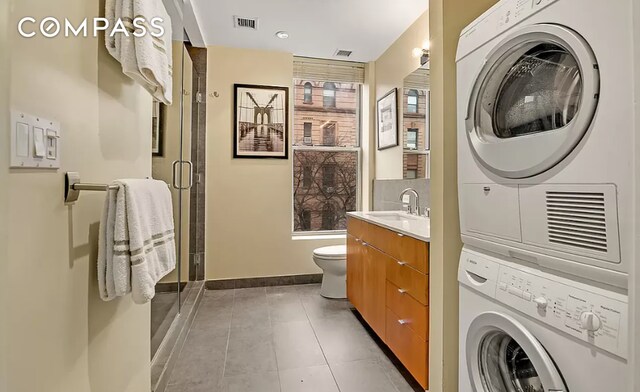 full bathroom with visible vents, toilet, stacked washer and clothes dryer, and a stall shower