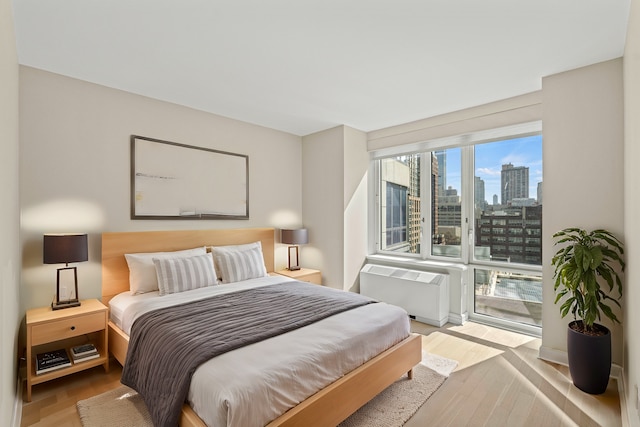 bedroom with wood finished floors, a city view, and radiator