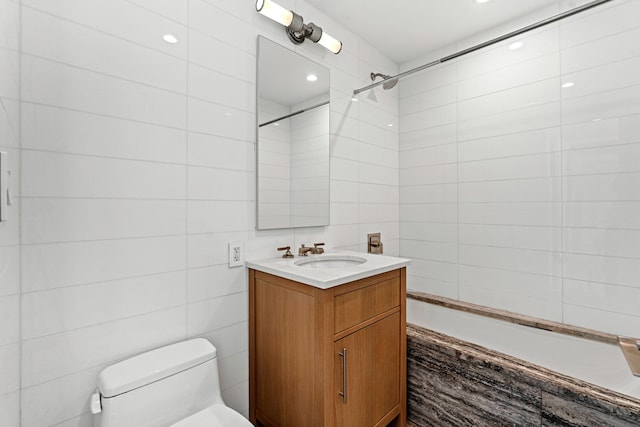 bathroom with tile walls, toilet, tub / shower combination, and vanity