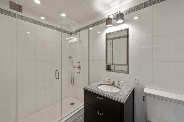 bathroom with vanity, a shower stall, crown molding, tile walls, and toilet