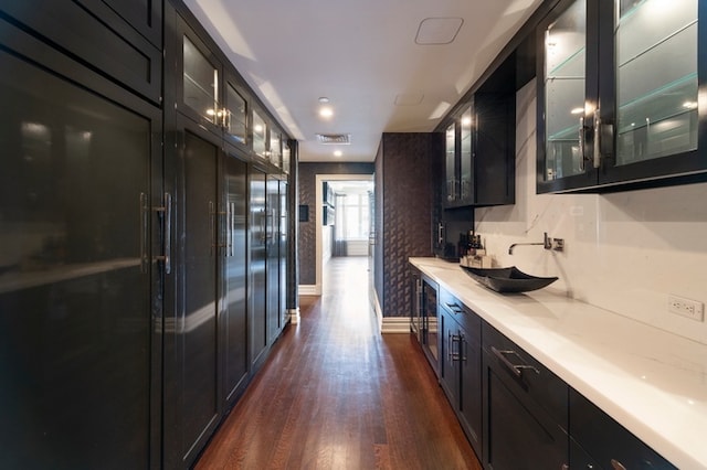 interior space featuring a sink, glass insert cabinets, dark wood-type flooring, and light countertops