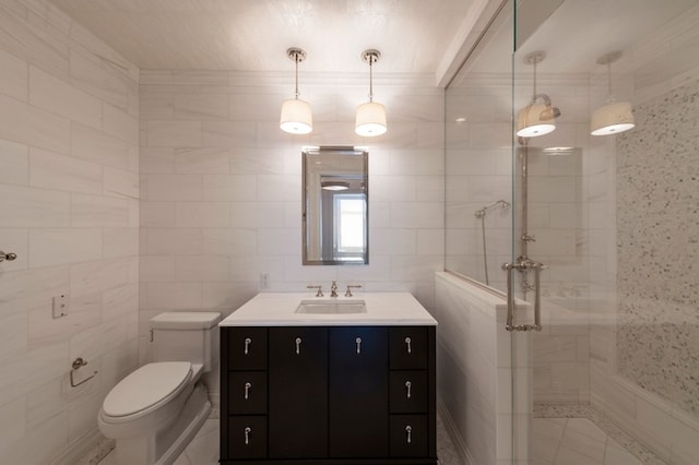 bathroom featuring vanity, tile walls, toilet, and a stall shower