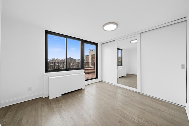 unfurnished bedroom featuring access to outside, baseboards, and wood finished floors