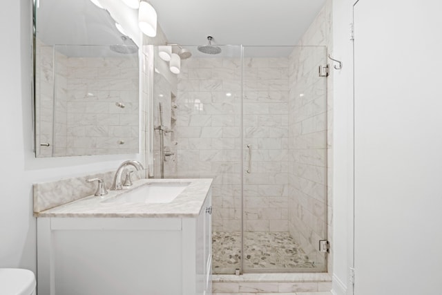 bathroom featuring toilet, a stall shower, and vanity